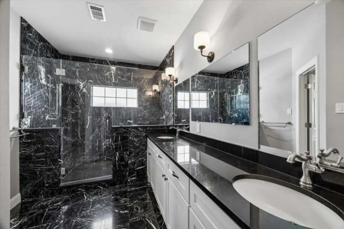 A private guest bathroom with a walk in shower, a long counter and two sinks