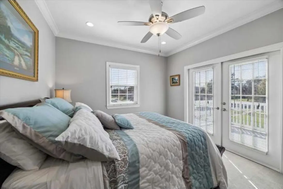 A guest bedroom with a queen bed, soft blue bedding and french doors to the upper deck