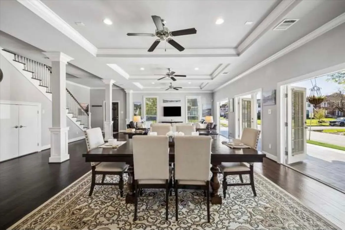 The dining room with a long table set for eight, under a tray ceiling