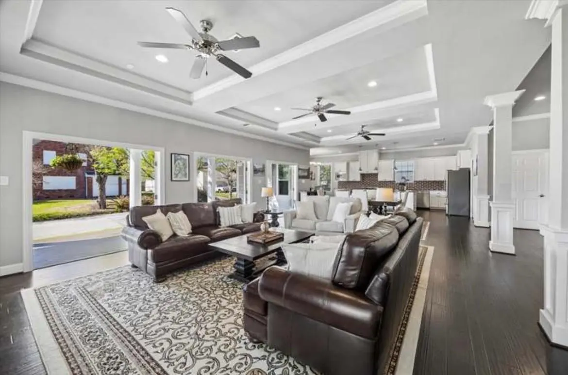 The open living room with sofas, a rug and french doors standing open onto the porch