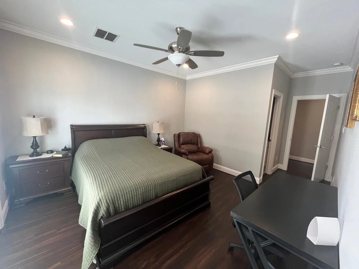 Room 2, with a queen bed under a green quilt, a brown recliner and a desk