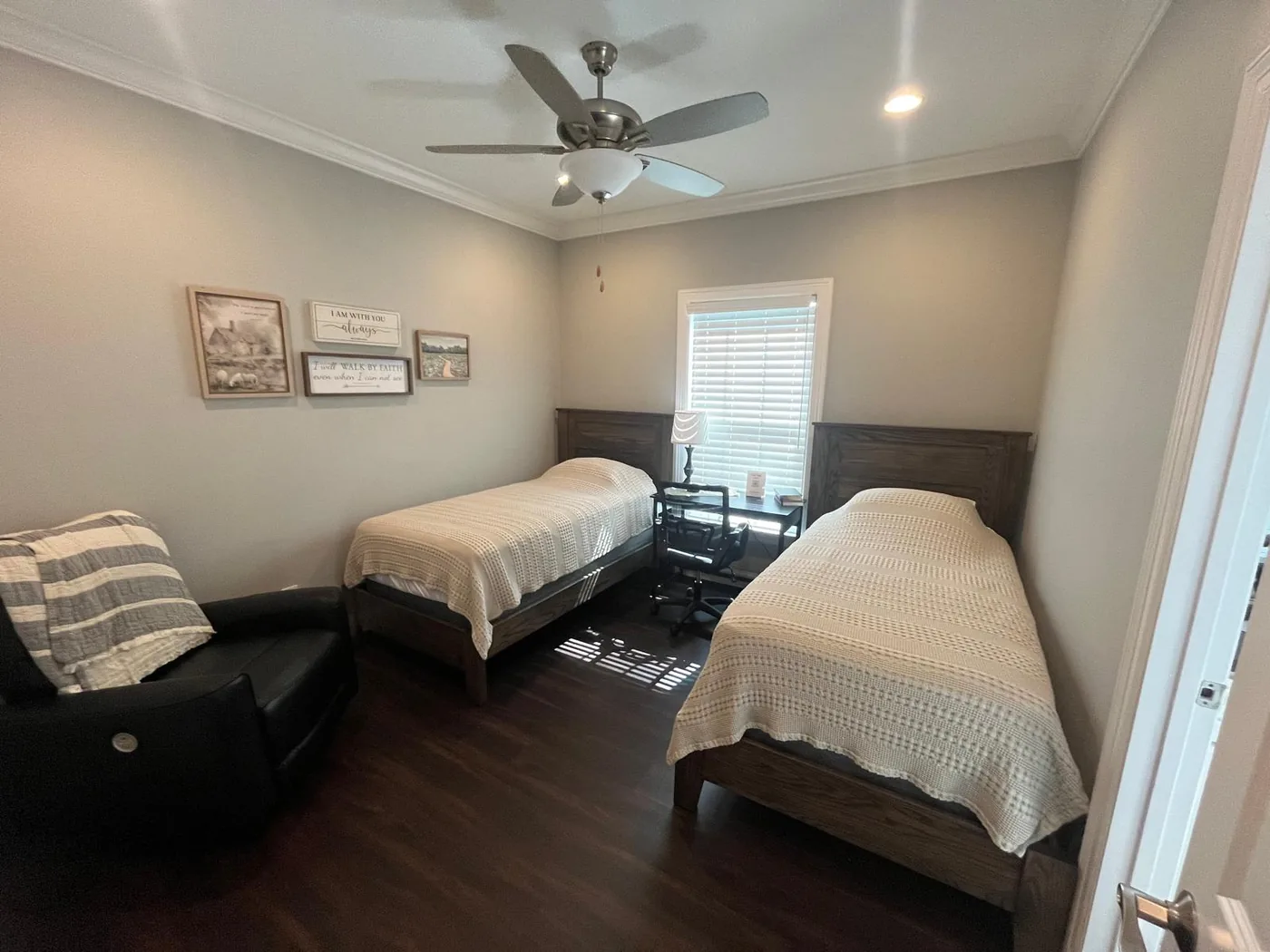 Room 4, with two twin beds, a black recliner and a desk under the window